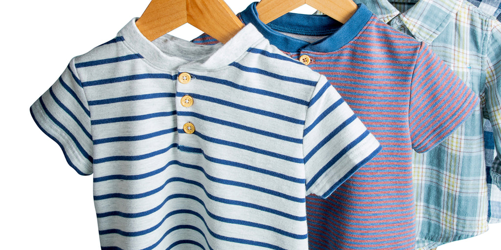 white shirt with blue stripes and 3 tan buttons on a wooden hanger with blue and red striped shirt behind it.
